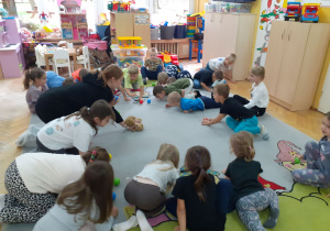 Dzieci poruszają się na czworakach i dmuchają na piłeczki