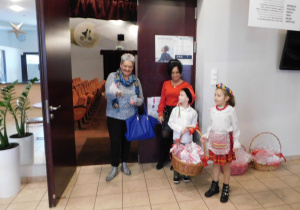 Dzieci w strojach krakowskich z panią Kamilką witają gości i częstują upominkowymi piernikami.