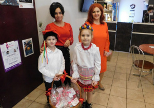 Dwoje dzieci z panią Dyrektor i panią Kamilką prezentują kosz pierników.
