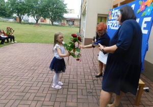 Martynka otrzymuje dyplom ukończenia przedszkola wraz z książką.