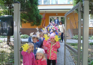 Przedszkolaki wychodzą z przedzskola sprzątać świat pokazując rękawice