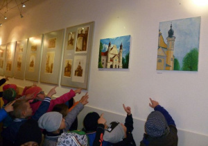 Sala wystawowa ŁDK, na ścianie w antyramach stare zdjęcia Łasku; grupa dzieci ogląda i wskazuje wybrane zdjęcia;