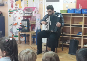 Pan Michał Mroziński gra na akordeonie.