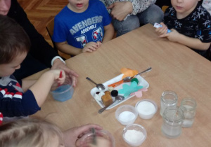Dzieci badają jaki kolor uzyskają mieszając w wodzie różne barwy farb.