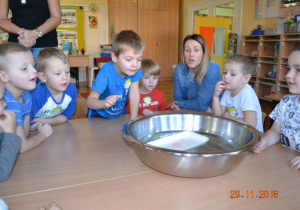 Dzieci wrzucają różne przedmioty do miski z wodą, sprawdzają co pływa co tonie