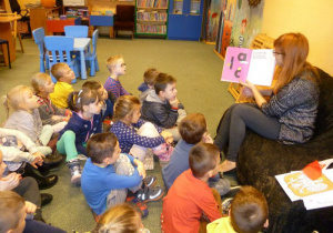 Prowadząca opowiada dzieciom pokazując ilustracje w książce.
