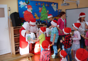 Mikołaj rozdaje ogromne paczki dzieciom.