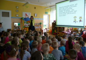 Dzieci oglądaja obraz na ekranie, prowadząca objaśnia tekst