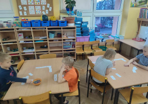Dzieci przy stolikach grają w matematyczne domino.