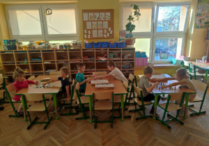 Dzieci przy stolikach grają w szachy i warcby.