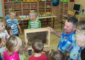 Pszczelarz pokazuje dzieciom jak pszczoły robią plastry miodu