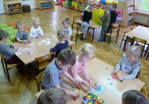 Dzieci pracują przy 3 stolikach: 1- układają domki z figur, przy 2 – układają domki z kart a przy 3 – budują domy z klocków;