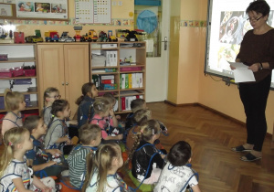 Wprowadzając dzieci w nastrój zbliżających się świąt Bożego Narodzenia pani Renia czyta wiersz „Wigilijny wieczór” i pokazuje na tablicy interaktywnej potrawy wigilijne królujące na polskich stołach.
