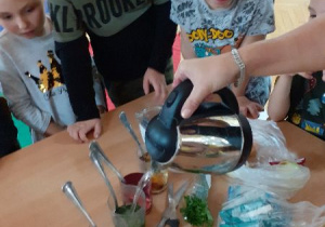 Lena, Karol, Antek i Kostek zachowują bezpieczeństwo podczas eksperymentowania.ników z owoców i warzyw w zabawie "Farbowanie ubrań"