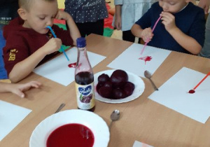 Filip i Fabian tworzą obrazek z soku wiśniowego w zabawie "Malowanie przez dmuchanie"