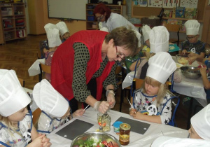 Dzieci przyglądają się jak pani Renia robi sos do sałatki.