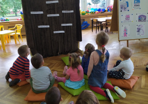 Dzieci oglądają teatrzyk kukiełkowy pt. "Bajka o kotku i kogutku" przedstawianą przez panią Ewę.