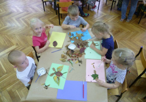 Przy stoliku: Filip, Julka, Kamil S., Maja i Zuzia przyklejają swoje kompozycje z liści.