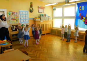 Dzieci z panią Ewą tańczą i śpiewają piosenkę „Trzy kółeczka”.