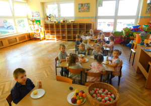 Dzieci siedzą przy stolikach podczas poczęstunku.