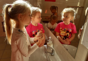 Dziewczynki demonstrują mycie rąk.