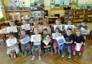 Dzieci z Żabek prezentują pomalowane przez siebie obrazki przedstawiające koronawirus.