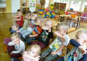 Dzieci demonstrują jak należy kasłać lub kichać w zagięcie łokcia;