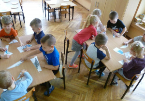 Dzieci z grupy "Krasnoludków" układają puzzle z pociętych obrazków przedstawiających komputery.