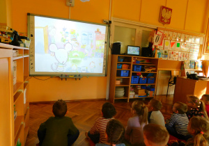 Dzieci na tablicy interaktywnej oglądają film pt. "Myszka w paski i dobre maniery".