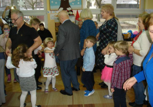 Dziadkowie tańczą poleczkę z wnuczkami.