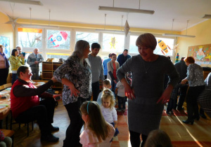 Dzieci wraz ze swoim babciami i dziadkami tańczą w parach taniec ludowy ,,Grozik