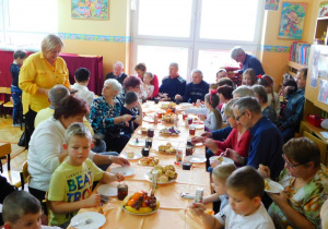 Dziadkowie z wnuczętami goszczą się przy zastawionym stole