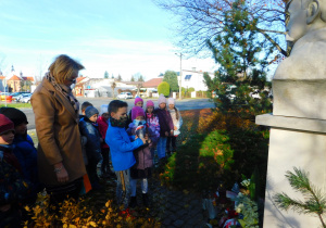 Dorotka i Emil trzymająi znicz pod Pomnikiem Józefa Piłsudskiego