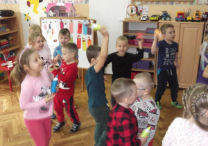 Przedszkolaki tańczą ze swoimi kredkami ilustrując treść piosenki „Kolorowe kredki”.