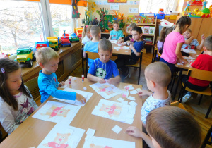 Dzieci z grupy Biedronek składają puzzle - misia