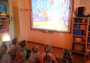 Dzieci oglądają film animowany z serii „Przygody Rozi.Pilnowanie małego misia”.