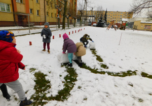 Lenka, Dorotka i Natan toczą śniegowe kule.