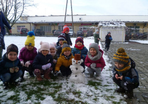 Grupka dzieci z Krasnoludków prezentuje ulepionego bałwanka.