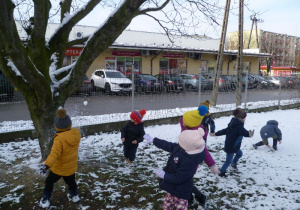 Dzieci celują śnieżkami w drzewo.