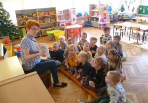 Pani Agnieszka czyta dzieciom książkę A.A. Milne „Kubuś Puchatek”.