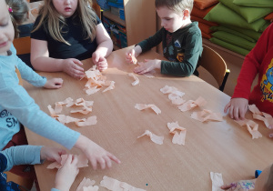 Dzieci uczą się, jak formować faworki z papierowych serwetek.