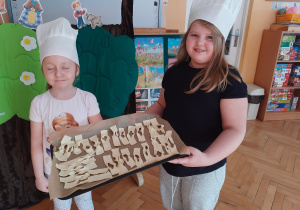 Oliwka i Zuzia prezentują faworki wykonane przez dzieci.