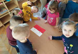 Żabki układają flagę Polski.