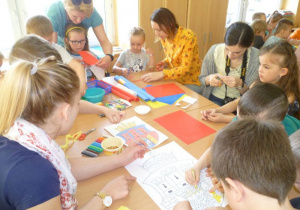  Przy dużym stole kilkoro dzieci i rodziców wycina, koloruje i wykonuje herb Krakowa;