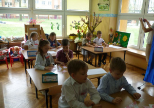 Dzieci przy stolikach wykonują zadanie konkursowe: układają z puzzli godło Polski