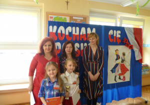 Trzy panie z jury stoją z Gabrysią i Jagną - reprezentantkami naszego przedszkola,na tle dekoracji;