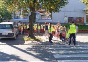 Dzieci kierują sie na ulicę, zatrzymują się przed przejściem