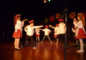 Na scenie, dziewczynki ustawione w kole klaszczą, chłopcy tańczą cwałem bocznym