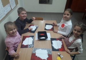 Lena, Karol, Zosia i Wiktoria podczas stemplowania farbami wokół mapy Polski.