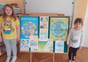 Zuzanna i Kornelia prezentują tablicę tematyczną przygotowaną z okazji Dnia Ziemi.